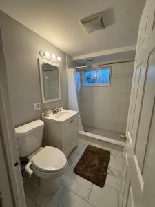 a white bathroom with a toilet and a sink at Comfort Stay by Stony Brook University & Hospital in Centereach