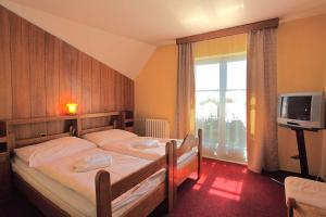 um quarto com 2 camas individuais e uma televisão em Hotel Tanecnica em Pustevny