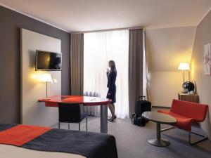 a woman standing in a hotel room looking out the window at Mercure Residenz Frankfurt Messe in Frankfurt/Main +91 photos