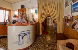 un homme assis au bar dans une pièce dans l'établissement Hotel Susa & Stazione, à Suse