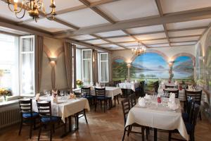 un restaurante con mesas y sillas blancas y una pintura en la pared en Jungfrau Hotel, en Wilderswil