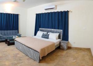 ein Schlafzimmer mit einem Bett mit blauen Vorhängen und einer Couch in der Unterkunft London lodges Guest House in Karatschi