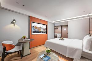 a hotel room with a large bed and a table at Huankai Hotel Pazhou Exhibition Center in Guangzhou