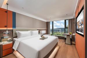 a large white bed in a room with a large window at Huankai Hotel Pazhou Exhibition Center in Guangzhou