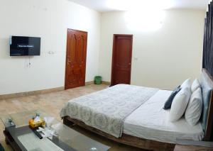 ein Schlafzimmer mit einem Bett und einem Fernseher an der Wand in der Unterkunft London lodges Guest House in Karatschi