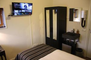 a bedroom with a bed and a tv on the wall at Casa Mirador Sleep Inn in Almere