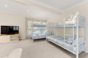 a bedroom with two bunk beds and a flat screen tv at Ocean Echoes - Pet Friendly with Ocean Glimpses in Culburra Beach