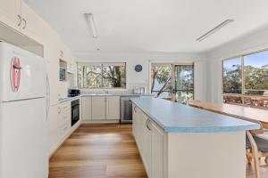 a kitchen with white cabinets and a blue counter top at Ocean Echoes - Pet Friendly with Ocean Glimpses in Culburra Beach