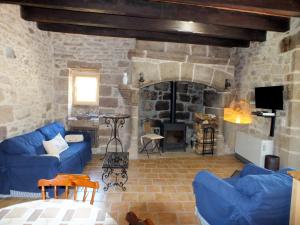 a living room with a blue couch and a stone fireplace at L'Oustal dè Pèiro in Le Bourg