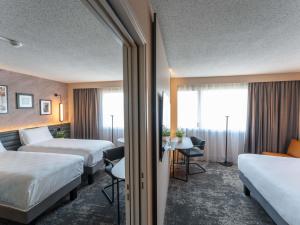 アンジェにあるNovotel Angers Lac de Maineのベッドが2つと窓があるホテルの部屋