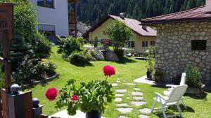 a garden with a chair and flowers in a yard at Residence La Planta in Ortisei
