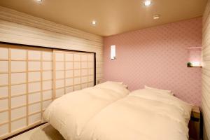 a bedroom with two white beds and pink walls at 善-zen- in Gujo