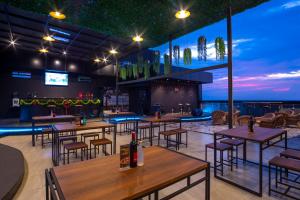 a restaurant with tables and chairs and a bar at Bono Hotel by ARTOTEL - Pekanbaru in Pekanbaru