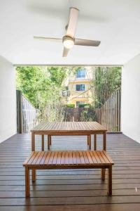 Un banco de madera en una terraza con un ventilador de techo. en Zen Garden - Serene Townhouse, en Gold Coast