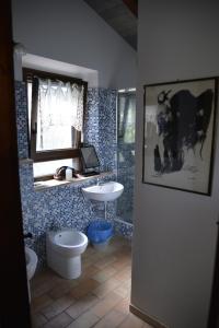 een badkamer met een wastafel, een toilet en een spiegel bij B&B Punto Magico in Offagna