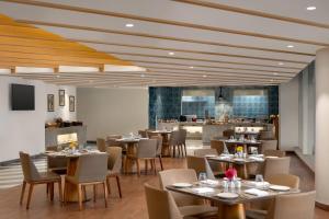 a restaurant with tables and chairs and a kitchen at Ramada Encore by Wyndham Lucknow Airport in Lucknow