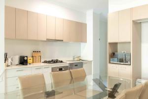 Una cocina con gabinetes blancos y una mesa de vidrio. en Zen Garden - Serene Townhouse, en Gold Coast