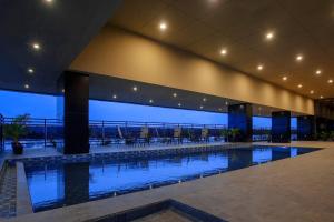 a large swimming pool in a building with a view at Bono Hotel by ARTOTEL - Pekanbaru in Pekanbaru