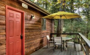 una terraza de madera con mesa y sombrilla en Cozy Cottage Rental with Small Private Pond in Canadensis, Pennsylvania, en Canadensis