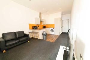 a living room with a black couch and a kitchen at Modern Central Blackburn 1 Bed Apartment in Blackburn