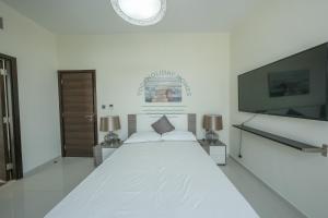 une chambre blanche avec un grand lit et une télévision à écran plat dans l'établissement Luxury 4BR Villa with Private Garden, à Dubaï