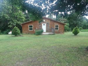 une petite maison en briques avec une porte blanche dans une cour dans l'établissement Farmhouse Cabin Getaway near Ozark Forest in Arkansas, à Marshall
