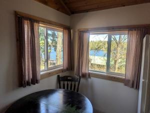 a dining room with a table and two windows at Secluded Lakeside Log Cabin Ideal for Couples Getaway' in Hayward, Wisconsin in New Post