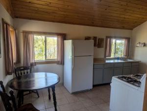 a kitchen with a table and a white refrigerator at Secluded Lakeside Log Cabin Ideal for Couples Getaway' in Hayward, Wisconsin in New Post
