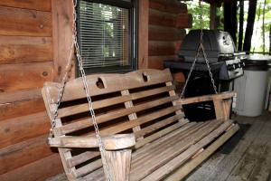 un banc en bois enchaîné à une cabine avec un gril dans l'établissement Stunning Pet-Friendly Cabin Rental near Charleston, West Virginia, à Hico