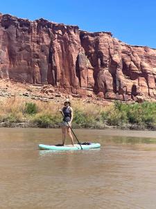 Una donna sta in piedi su una tavola da paddle in acqua di Rustic Family Glamping Tent for Outdoor Adventure Lovers by the Colorado River in Moab, Utah a Allen Memorial Hospital Heliport