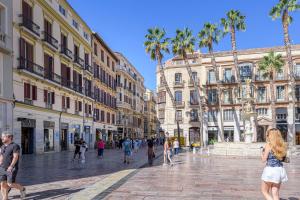 Un grupo de personas caminando por una calle con palmeras. en iloftmalaga Pasaje Chinitas, en Málaga
