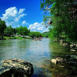 a river with a group of people standing on the banks at Glamping Adventure on the Guadalupe River: Cool Bell Tent near New Braunfels, Texas Perfect for All Ages in Second Crossing