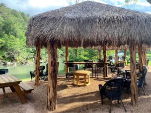 a straw hut with tables and chairs and a table at Glamping Adventure on the Guadalupe River: Cool Bell Tent near New Braunfels, Texas Perfect for All Ages in Second Crossing +22 photos