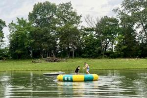 two people are standing on a raft in the water at Outstanding Lakefront Cabin in Makanda, Illinois in Sunset Harbor