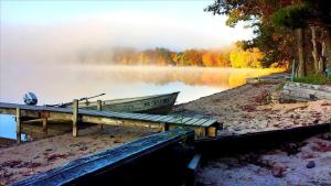 un quai avec deux bateaux sur la rive d'un lac dans l'établissement Spacious Family-Friendly Log Cabin with Lake Views near Cadillac, Michigan, à Wellston 2 autres photos