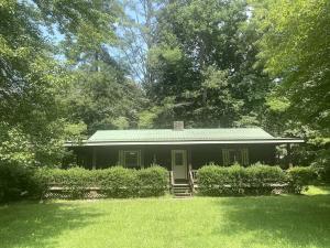 a small house with a green roof in a yard at Rustic Log Cabin Rental near Chattahoochee National Forest, Georgia in Hiawassee