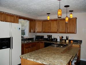 a kitchen with wooden cabinets and a white refrigerator at Simple Camping Cabin on Eight Private Forested Acres near Brevard, North Carolina in Cedar Mountain