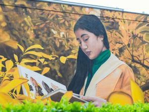 uma mulher lendo um livro em frente a uma pintura em Mercure Metz Centre em Metz