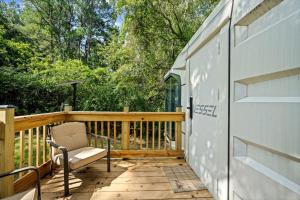 a wooden deck with a chair and a building at Modern Airstream Glamping with Pond Views in Rural South Carolina in Saint Stephen