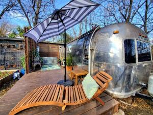 a chair and an umbrella in front of a trailer at Sleek Retro Airstream Rental for Glamping for Two near Downtown Austin in Austin