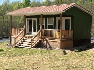una piccola casa verde con portico e scale di Cozy Cabin in the Idyllic Blue Ridge Mountains, Virginia a Konnarock