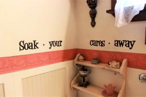 ein Badezimmer mit Toilette und etwas Schrift an der Wand in der Unterkunft Rustic Victorian-Style Cottage Rental with Clawfoot Bathtub on Hamilton Creek, Texas in Marble Falls + 16 Fotos