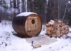 a wooden barrel with a pile of logs in the snow at Beautiful Cabin Surrounded by Stunning Nature in Wilmington, New York in Wilmington