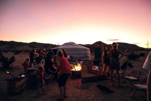 a group of people standing around a fire at sunset at Remote Yurt Amazing for Stargazing near Joshua Tree National Park, California in Sunfair Heights