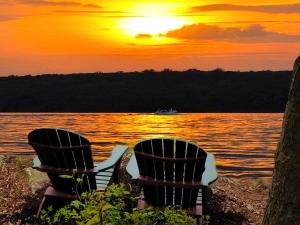 two chairs sitting on the beach watching the sunset at Lakefront Cabin Rental with Incredible Sunsets on Lake Wallenpaupack, Pennsylvania in Tafton