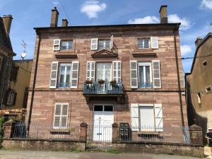 an old brick house with white windows and a balcony at Chez Bles appartement in Luxeuil-les-Bains