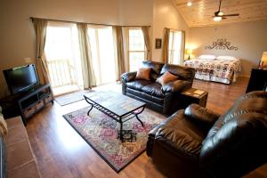 ein Wohnzimmer mit Ledermöbeln und einem Bett in der Unterkunft Lakefront Cozy Cabin with Hot-tub in Carbondale, Illinois in Etherton