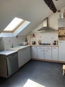 a large kitchen with white cabinets and a skylight at Chez Bles appartement in Luxeuil-les-Bains +3 photos