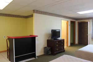 a room with a bed and a tv on a dresser at Berkshire Travel Lodge in Canaan
