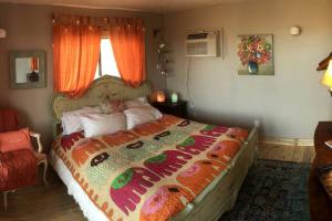 - une chambre avec un grand lit et un rideau orange dans l'établissement Romantic Yucca Valley Cabin with Hot Tub, à Yucca Valley